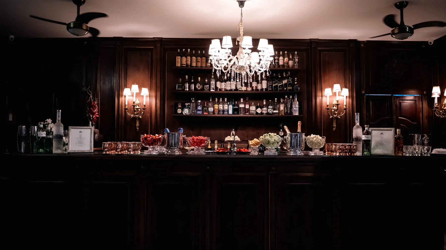 Bar de madeira escura com lustre de cristal, visto de frente